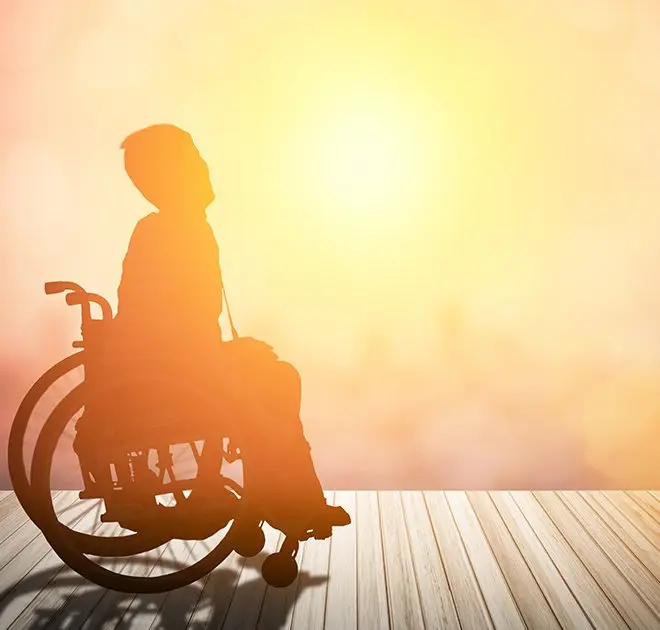 person sitting in a wheelchair at sunset