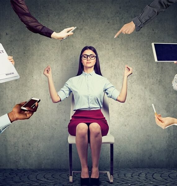 woman peacefully meditating in the workplace while surrounded by chaos