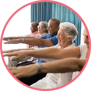 group of smiling people practising chair yoga with their arms stretched out