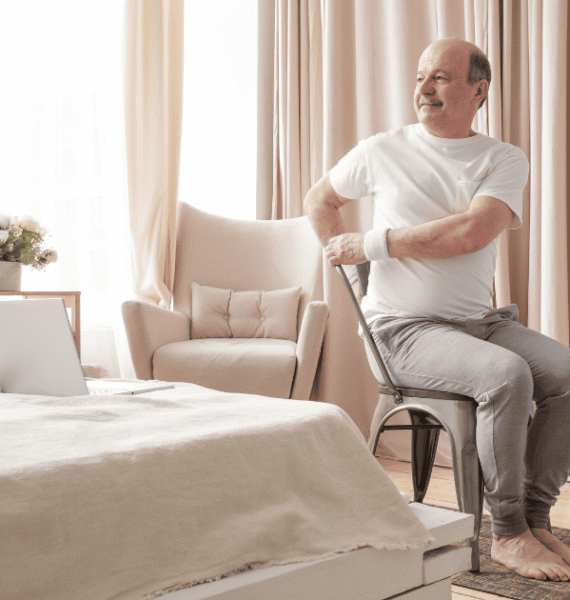 man practising chair yoga at home